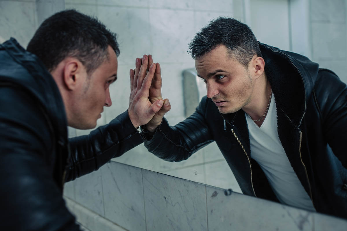 Man with black eye looking at himself in the mirror