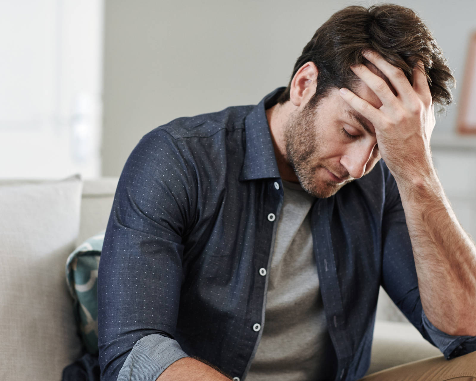 Man sitting down holding his head