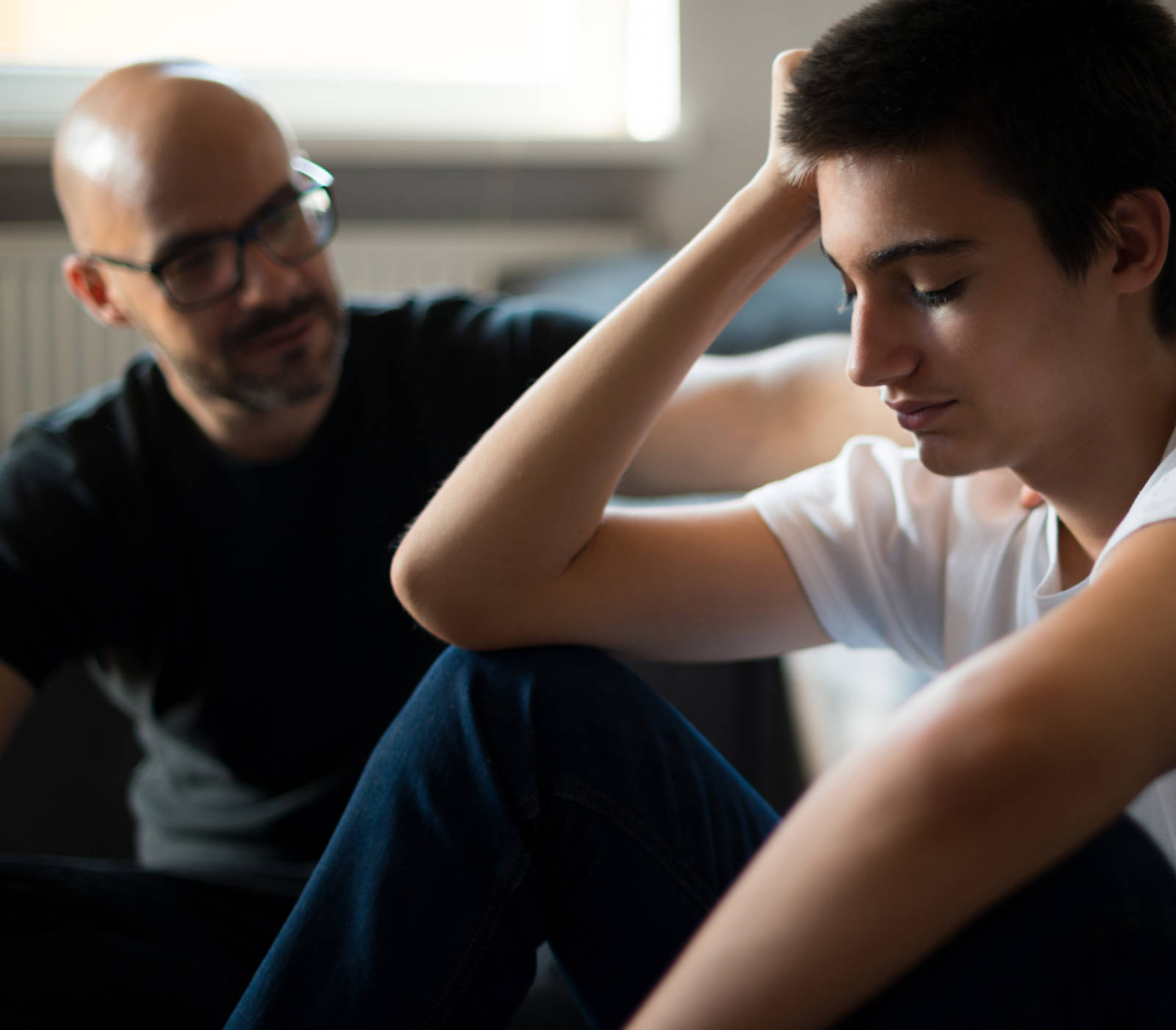 man sitting down with a young man that looks sad