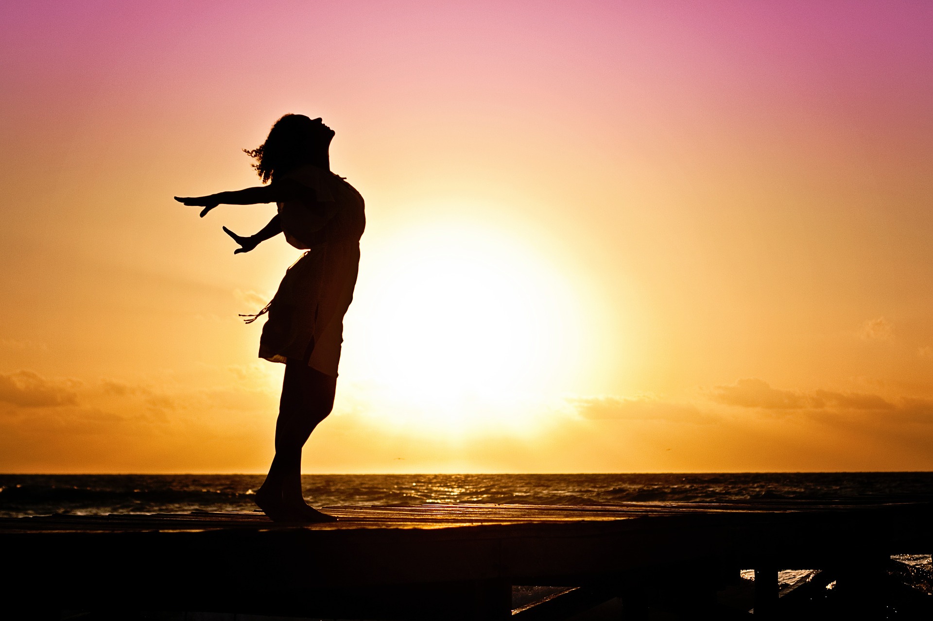 Woman on the beach during sunset embracing the fresh air and sun