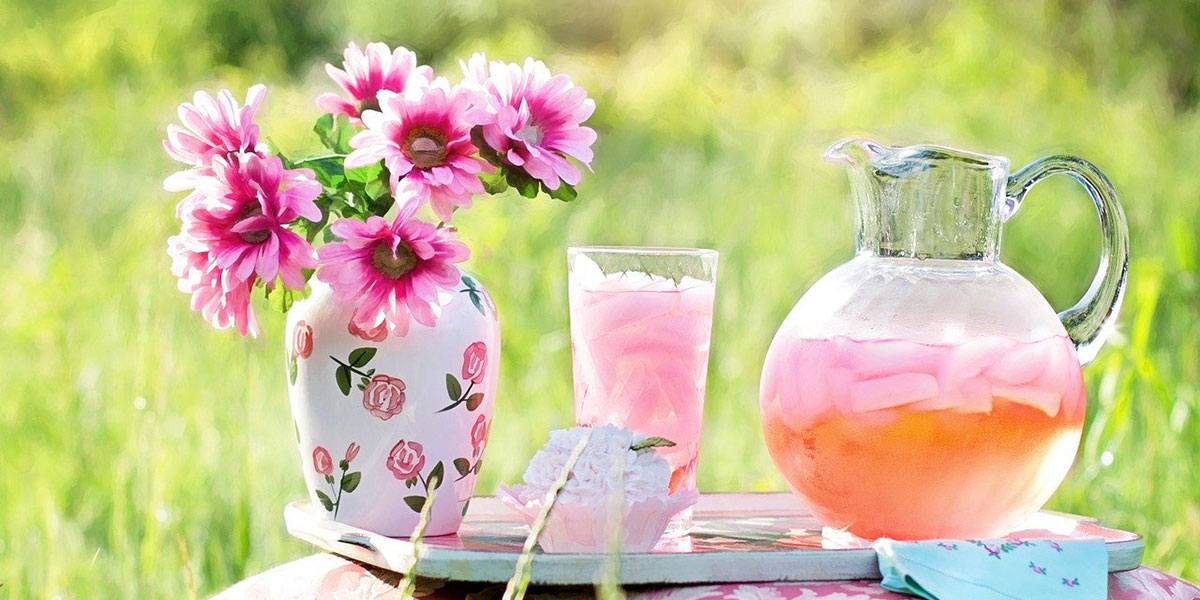 Summer pink flower with glass and pitcher of pink lemonade