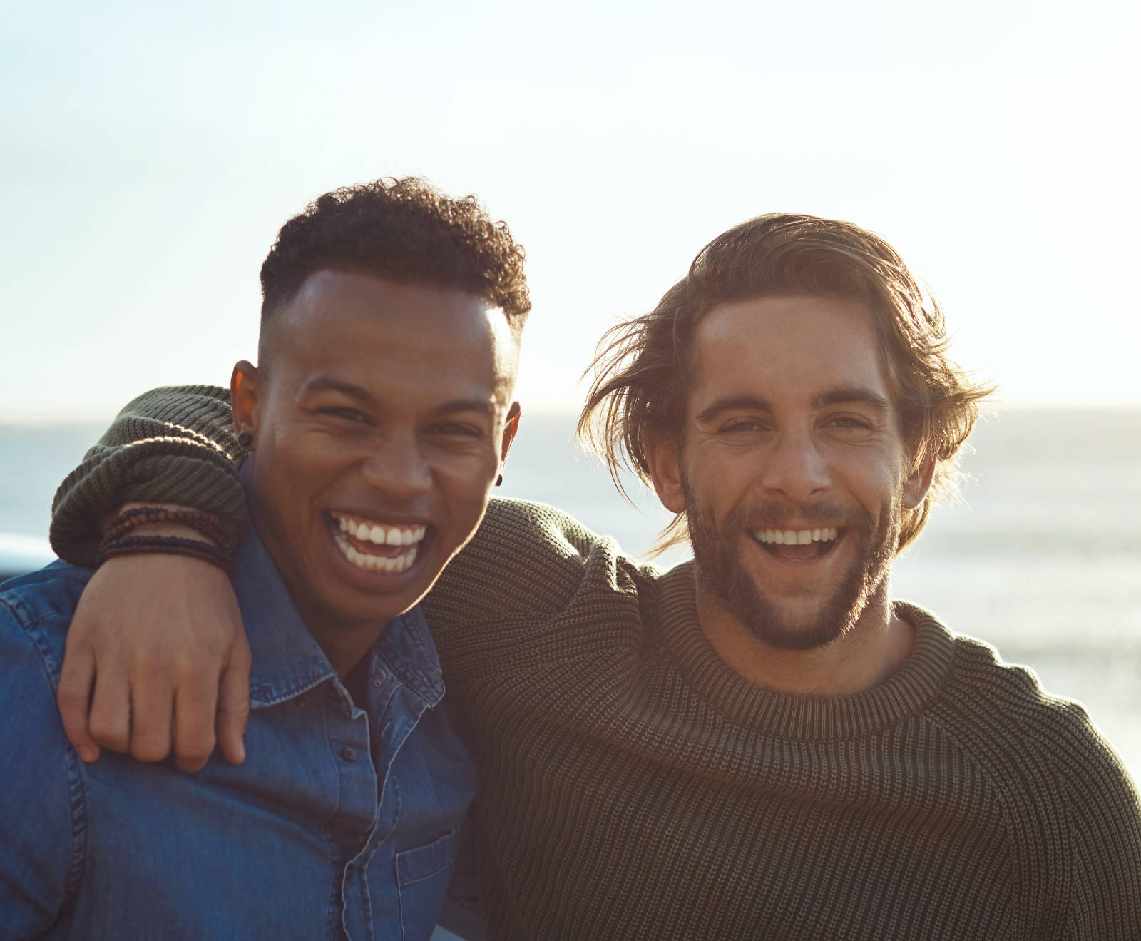 two men smiling standing in front of the ocean
