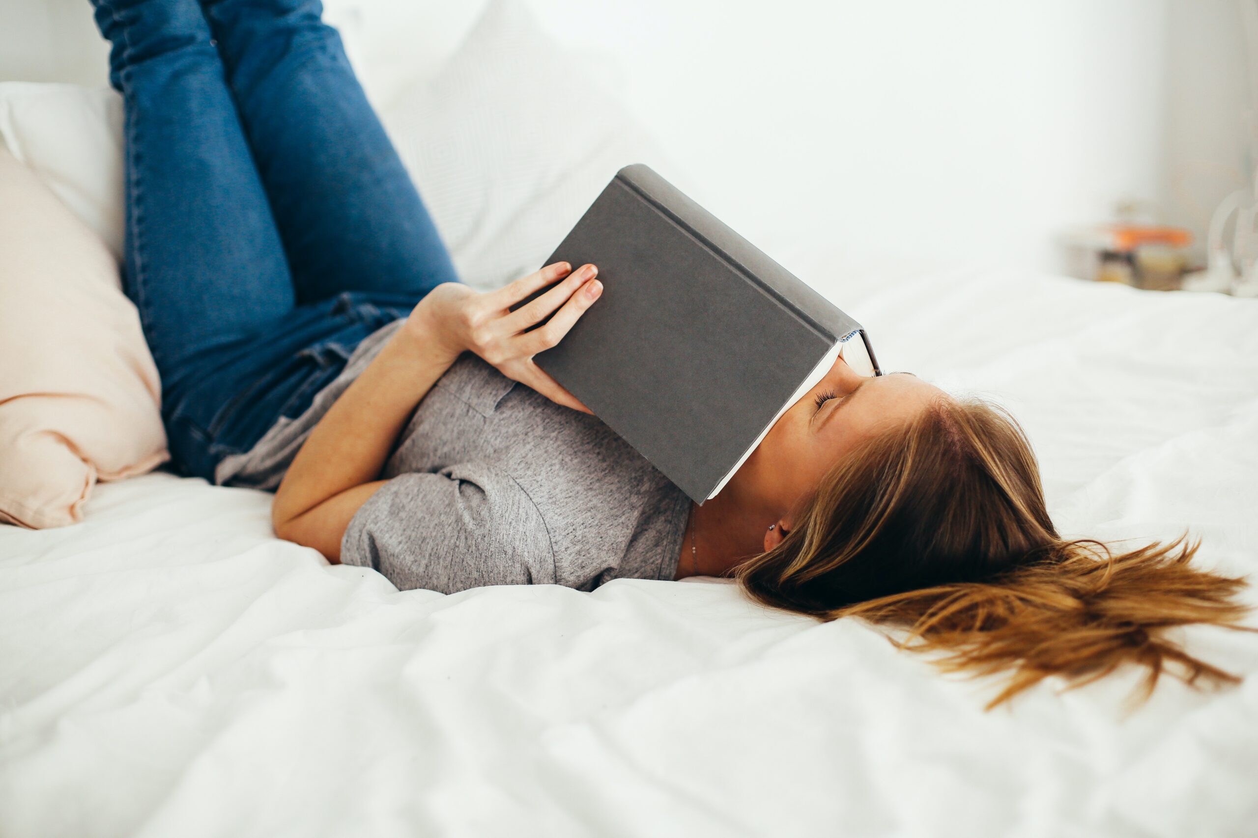 person laying down with a book over their face