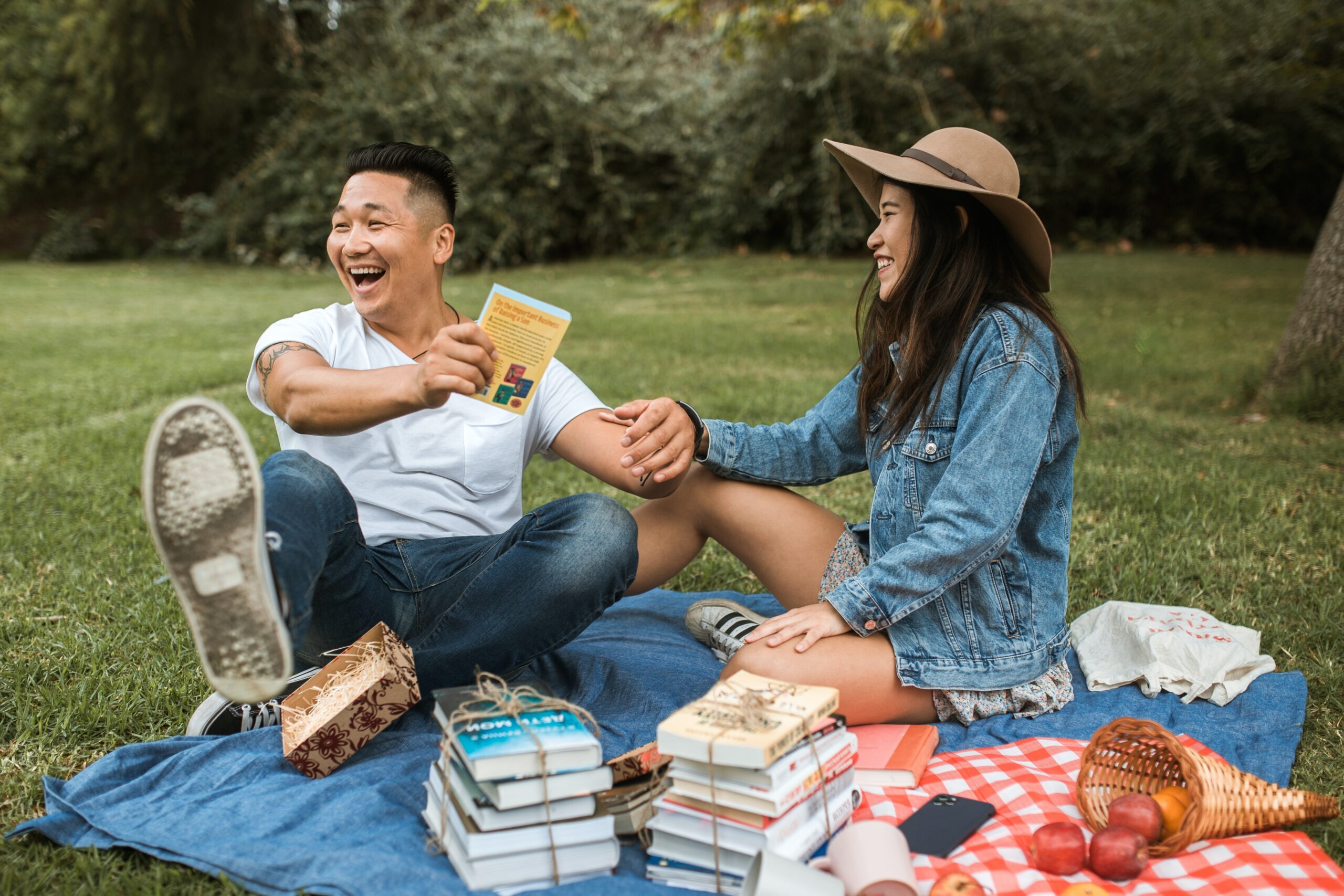 man and woman sitting on blanket discussing books