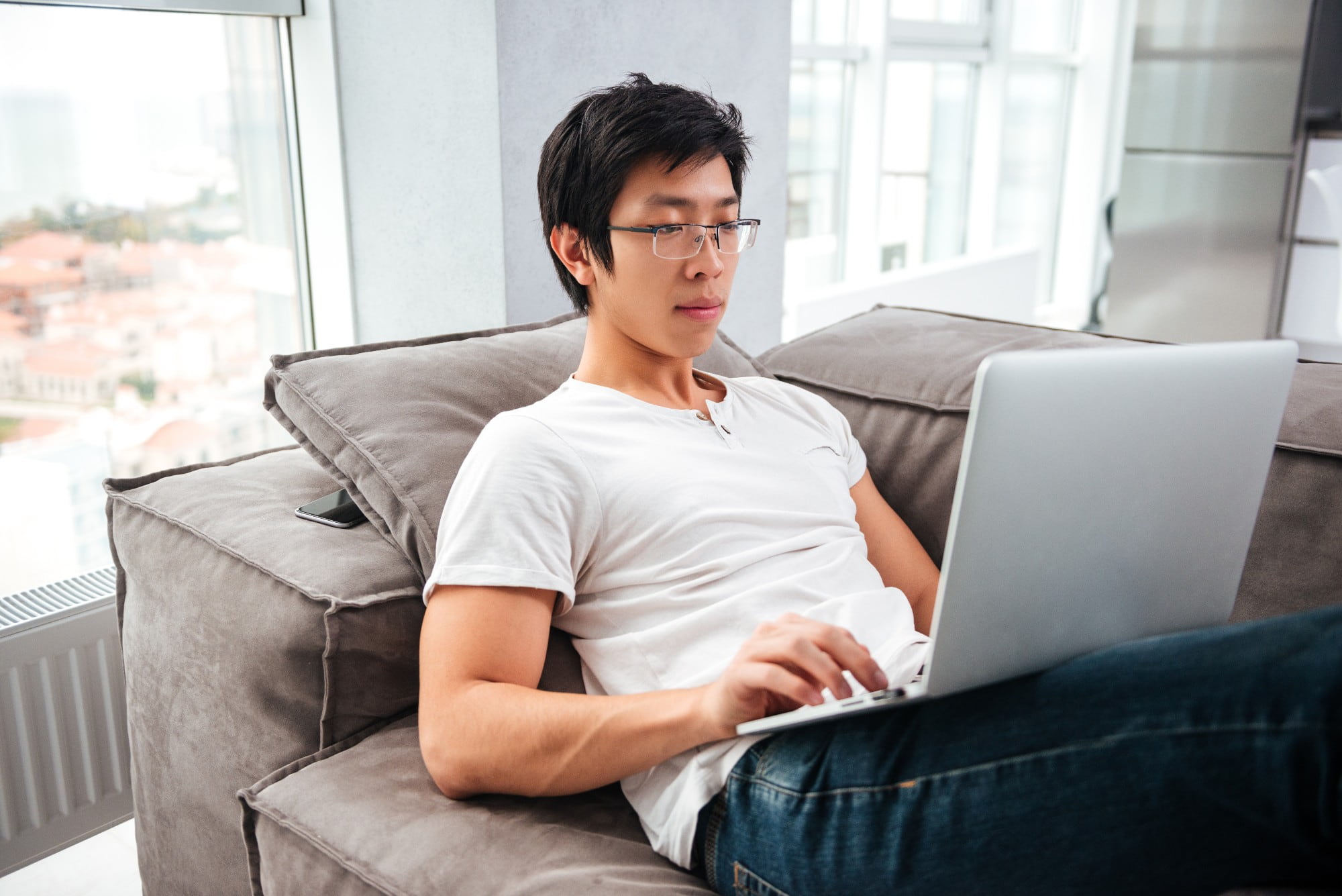 Man sitting down on a couch looking at a laptop