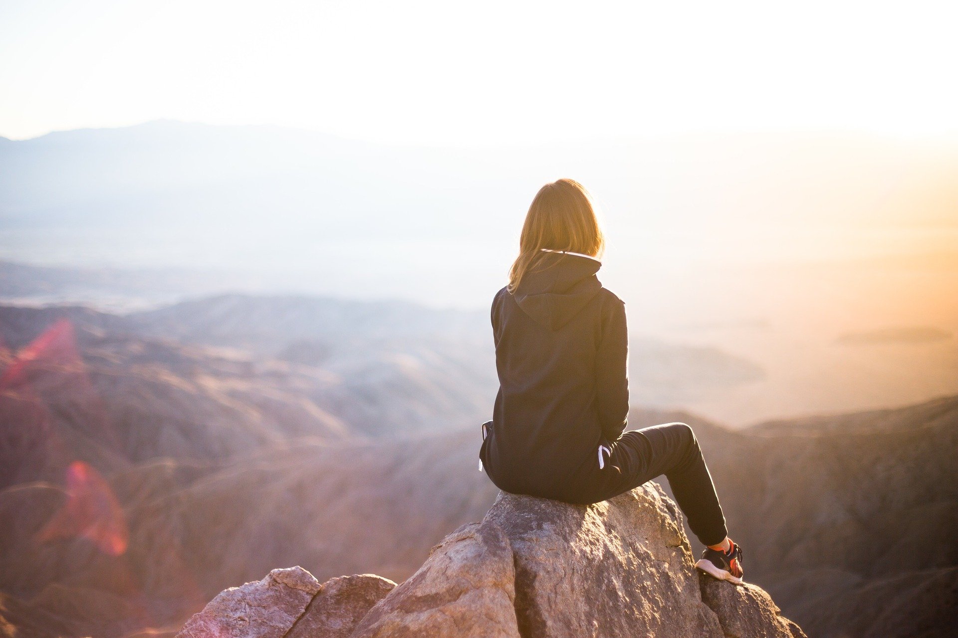 Woman sitting on rock over looking mountains
