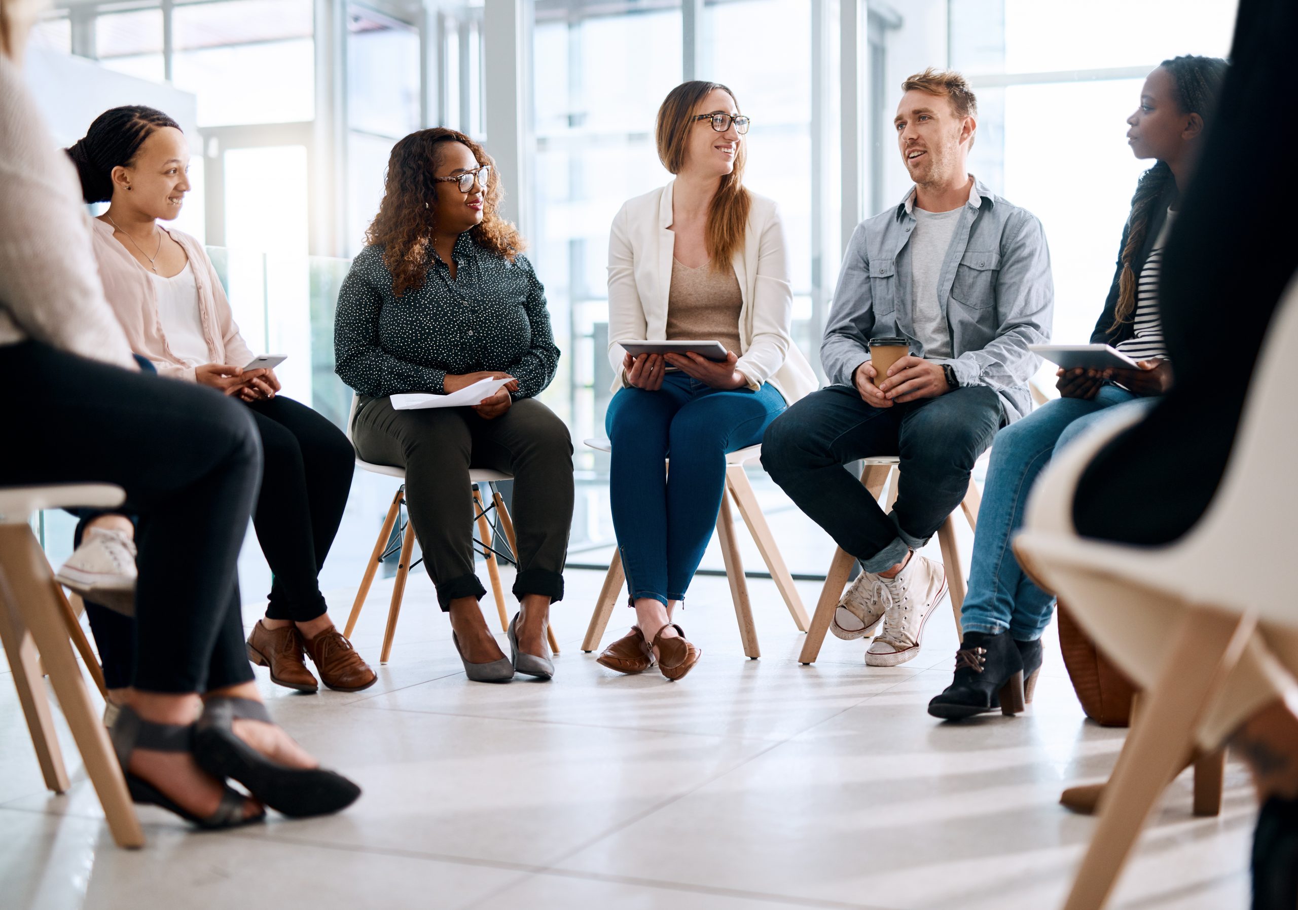 Round of people sitting happily discussing their meeting in a modern office