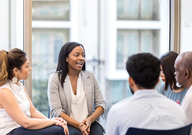 Young woman leading group therapy session.