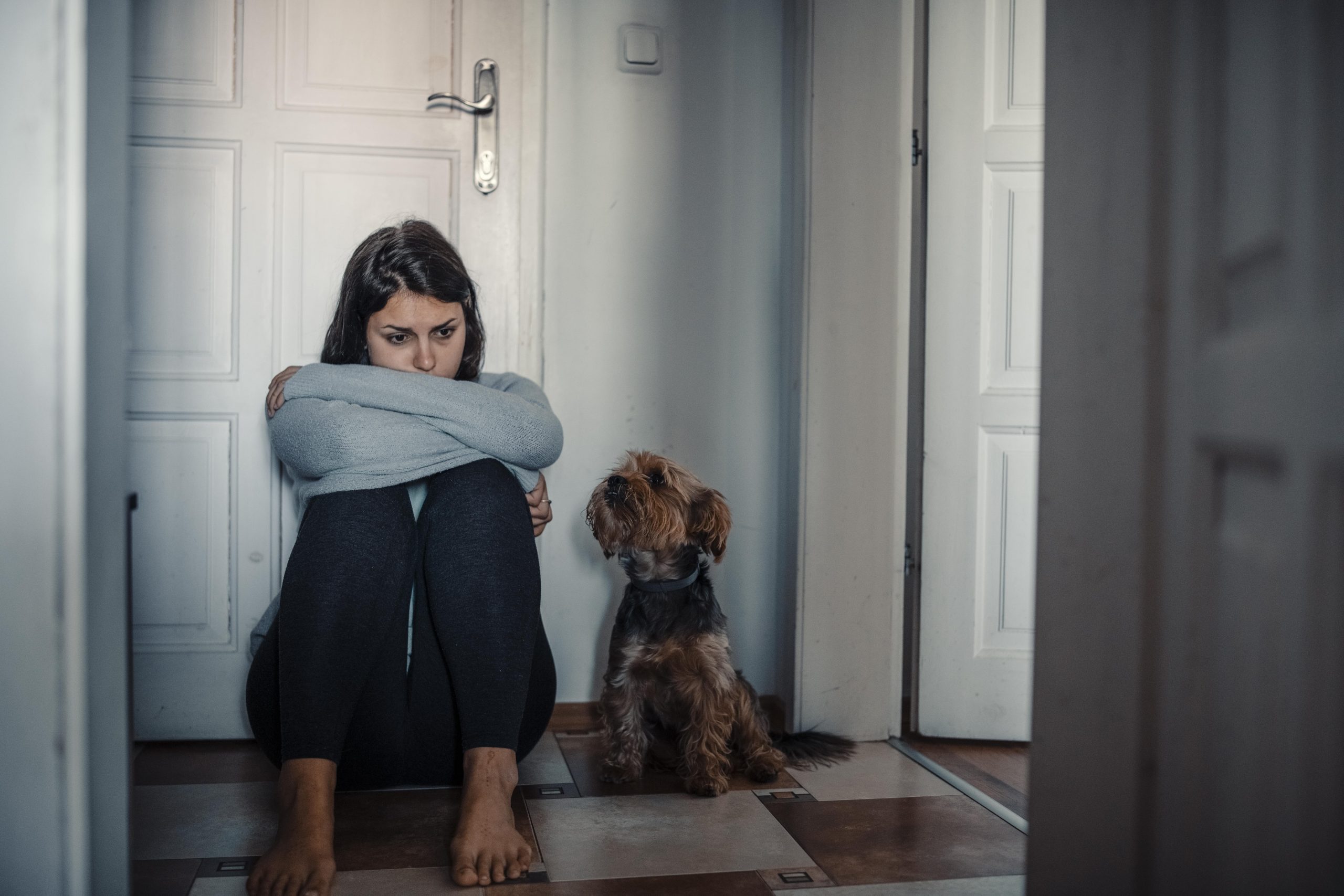woman looking sad while dog sits next to her