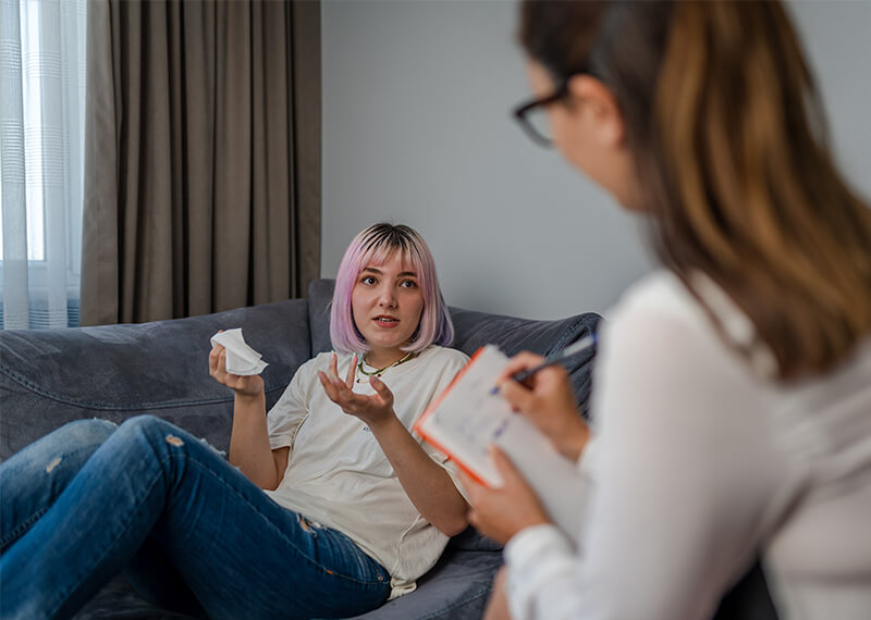 Woman talking to her therapist who is taking notes