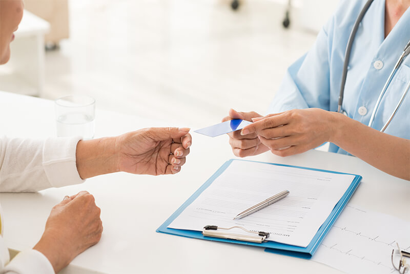 Patient handing their insurance card to clinic employee