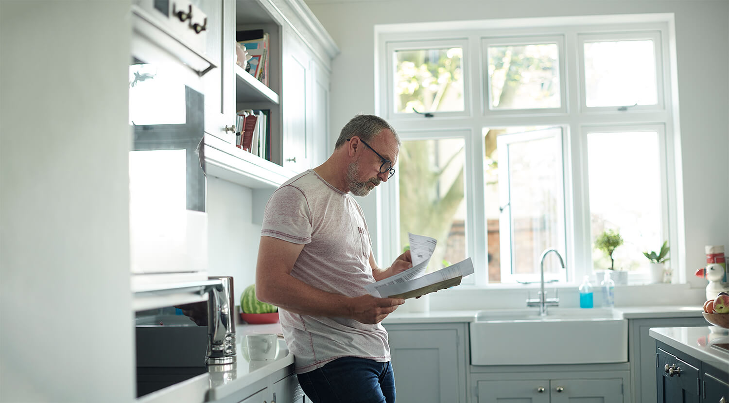 Man looking at bills in his kitchen