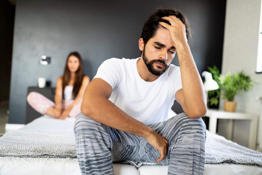 man sitting down on a couch with woman sitting behind him