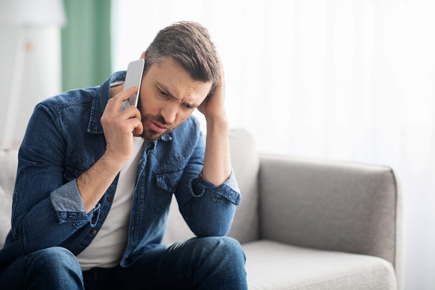 man sitting down on a couch talking on the phone