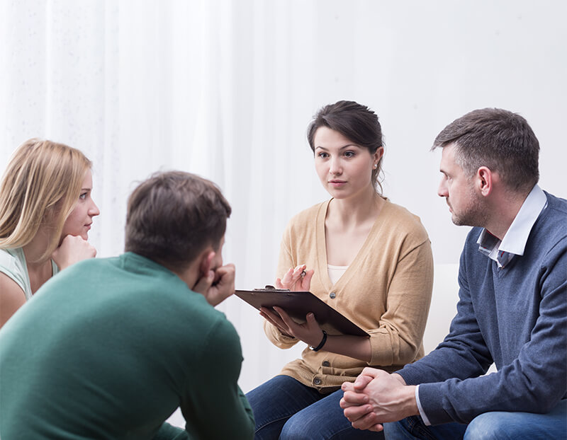 Therapist with clipboard leading group therapy session