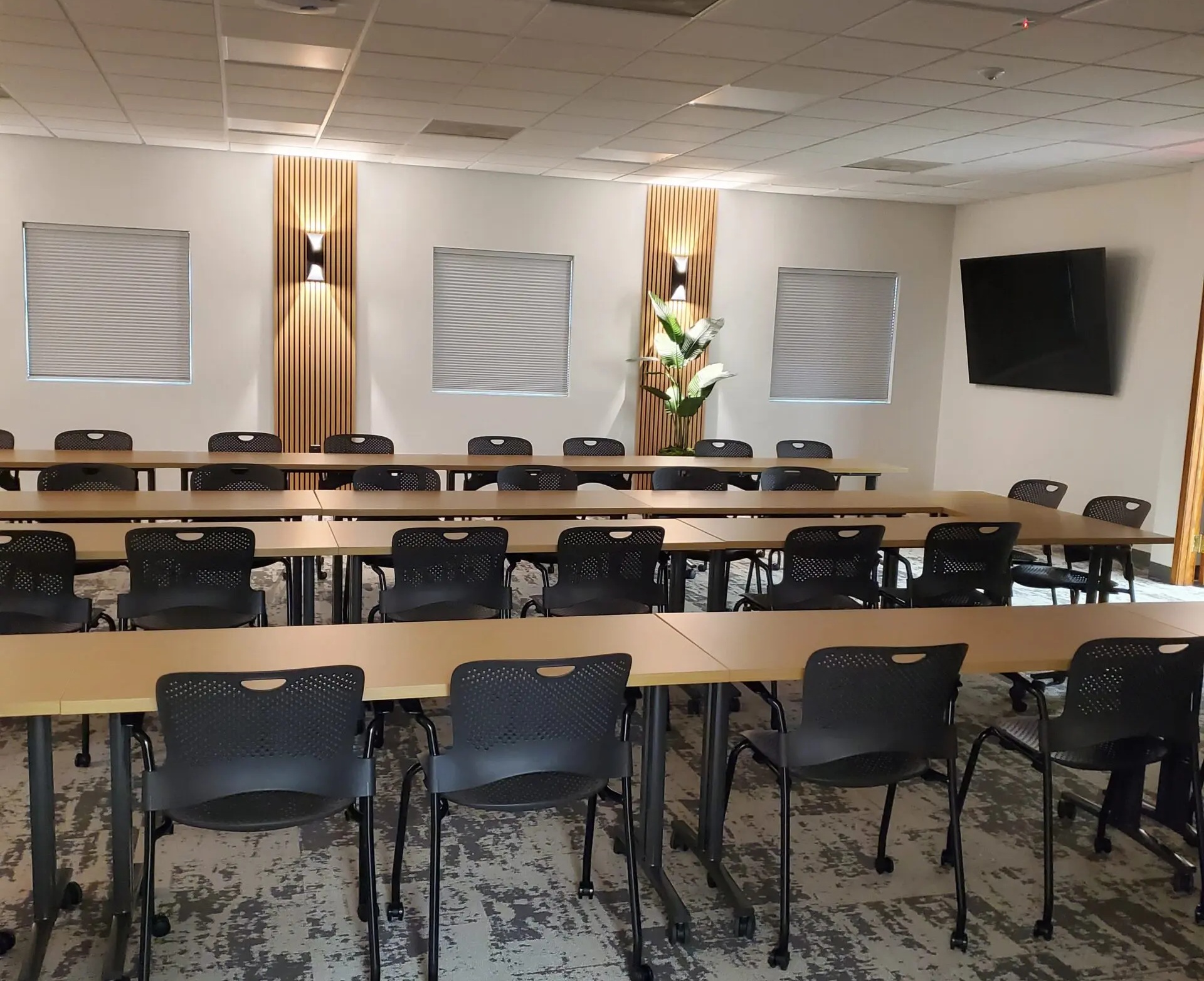 Classroom style seating with a TV on the wall and long tables in four rows