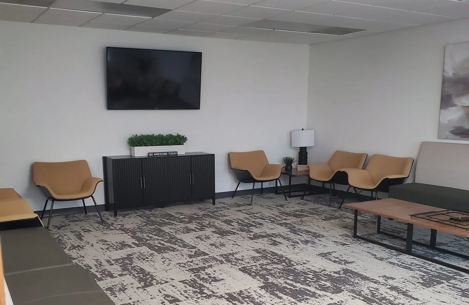 Interior seating lobby with modern seats against the wall and a TV on the wall