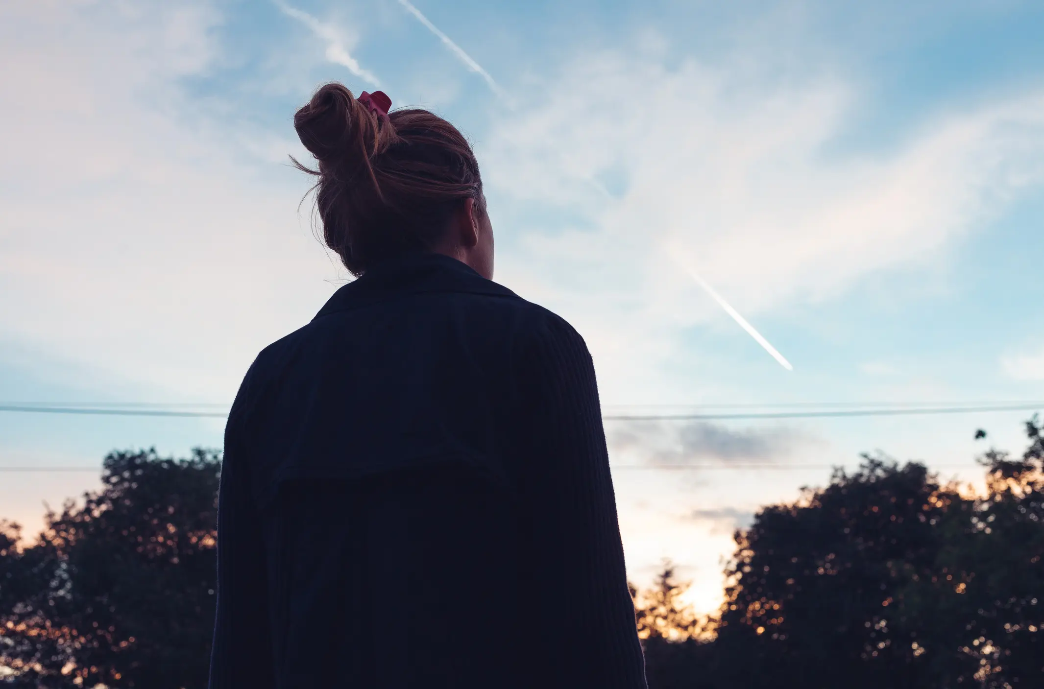 A woman in recovery for alcohol use disorder looking up at the sky
